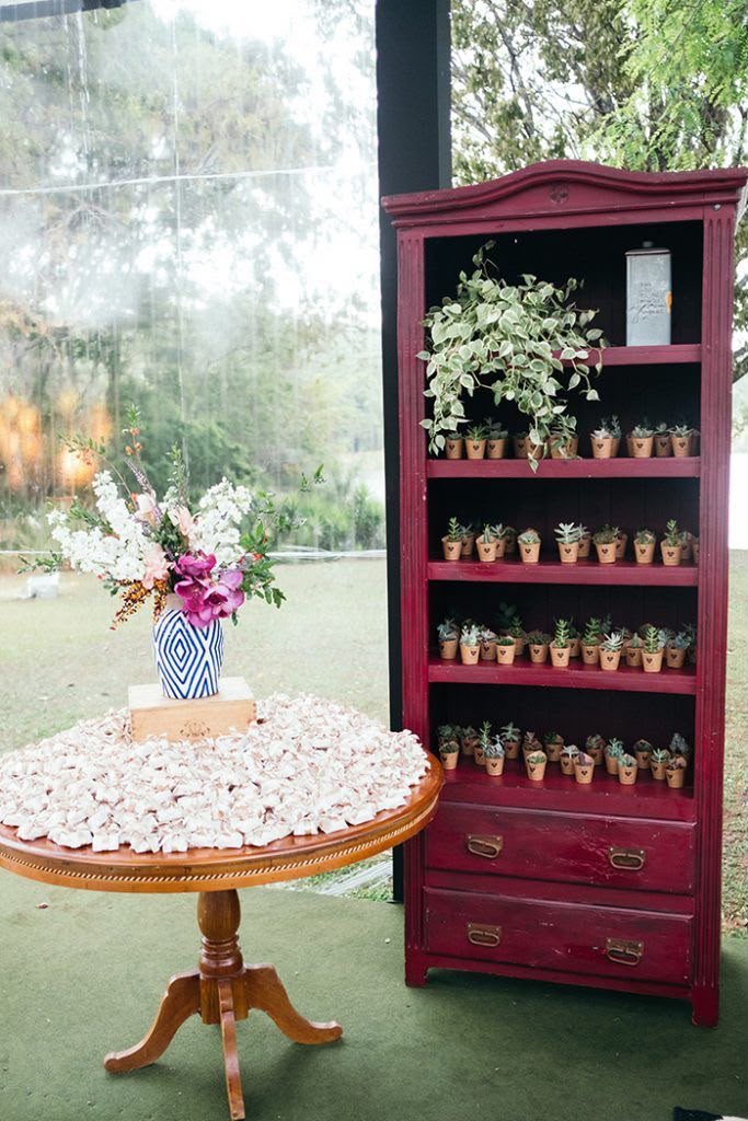 Mesa com lembrancinhas embaladas e mini vasinhos em estante